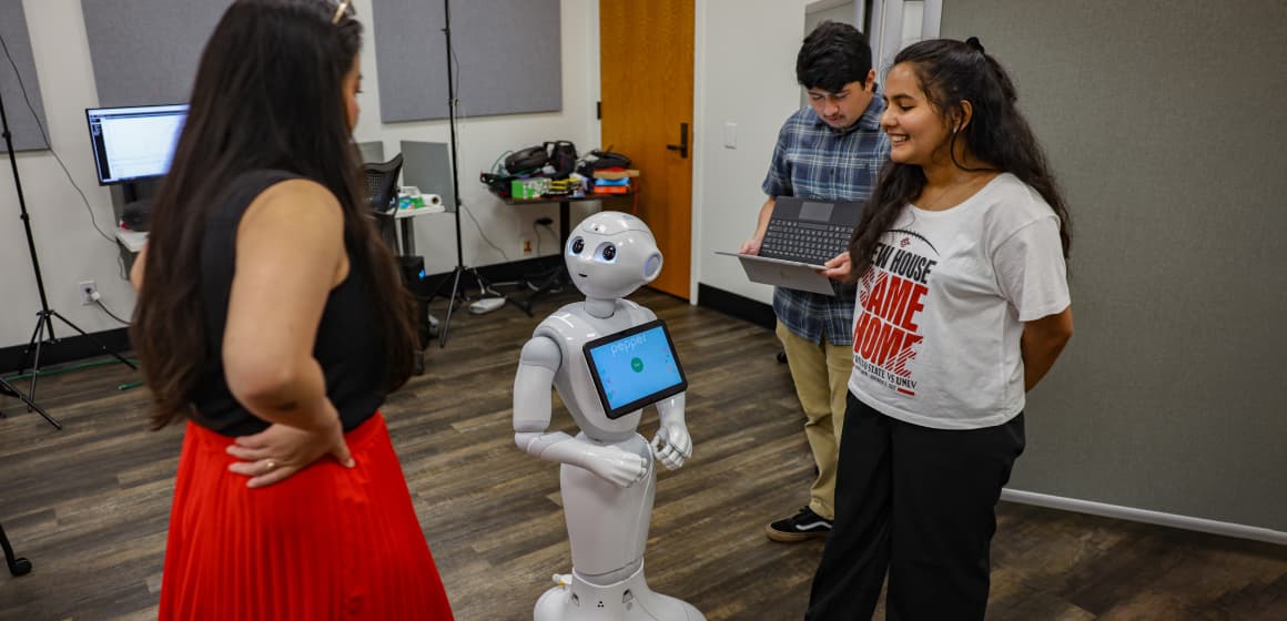 Student talking to instructor and a robot